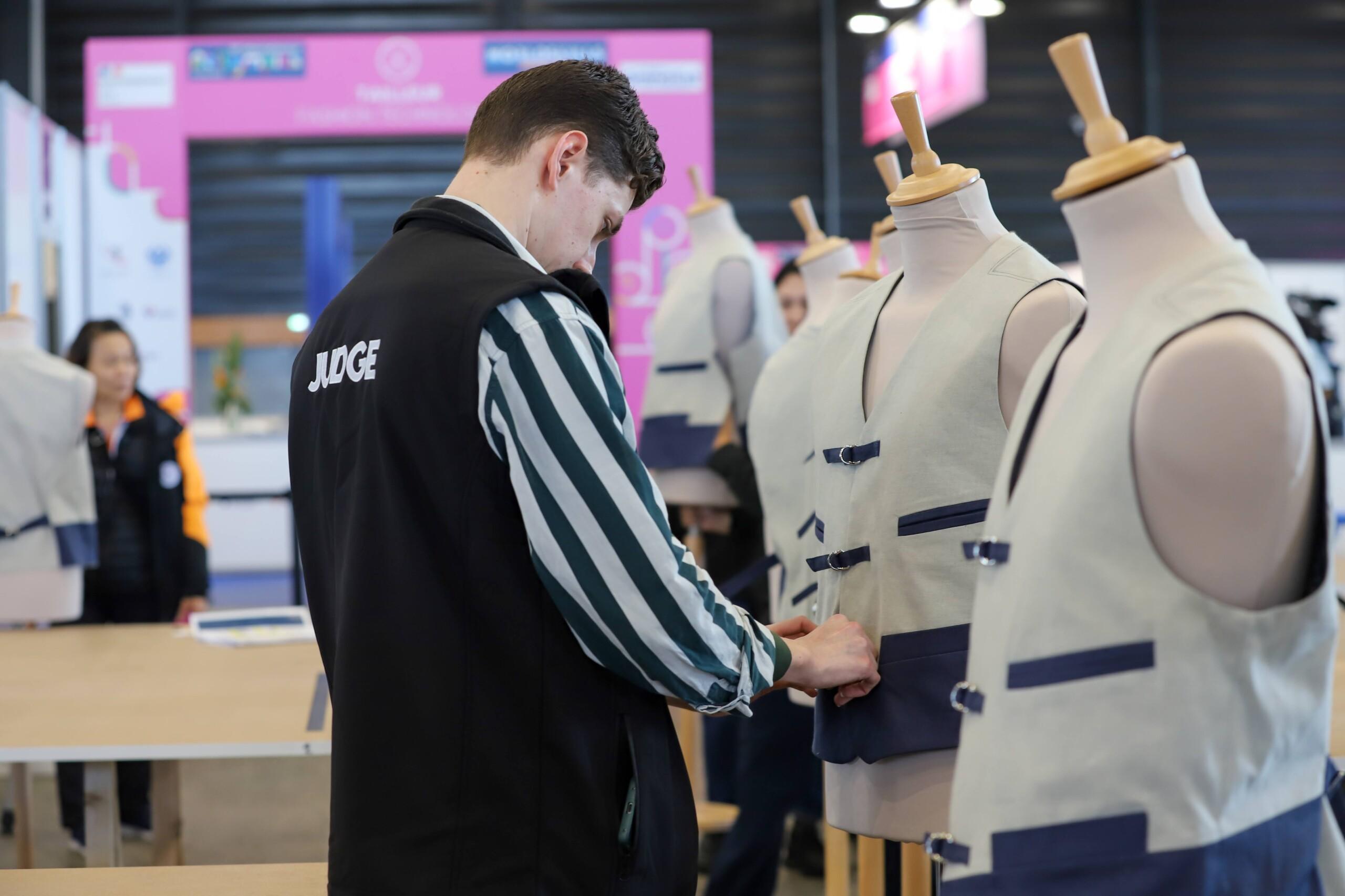 Person adjusting a waistcoat on a mannequin.