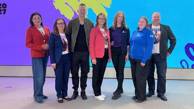 Speakers and organizers of the Skills Games 2027 opening broadcast posing for a group photo in front of the event’s colorful backdrop.
