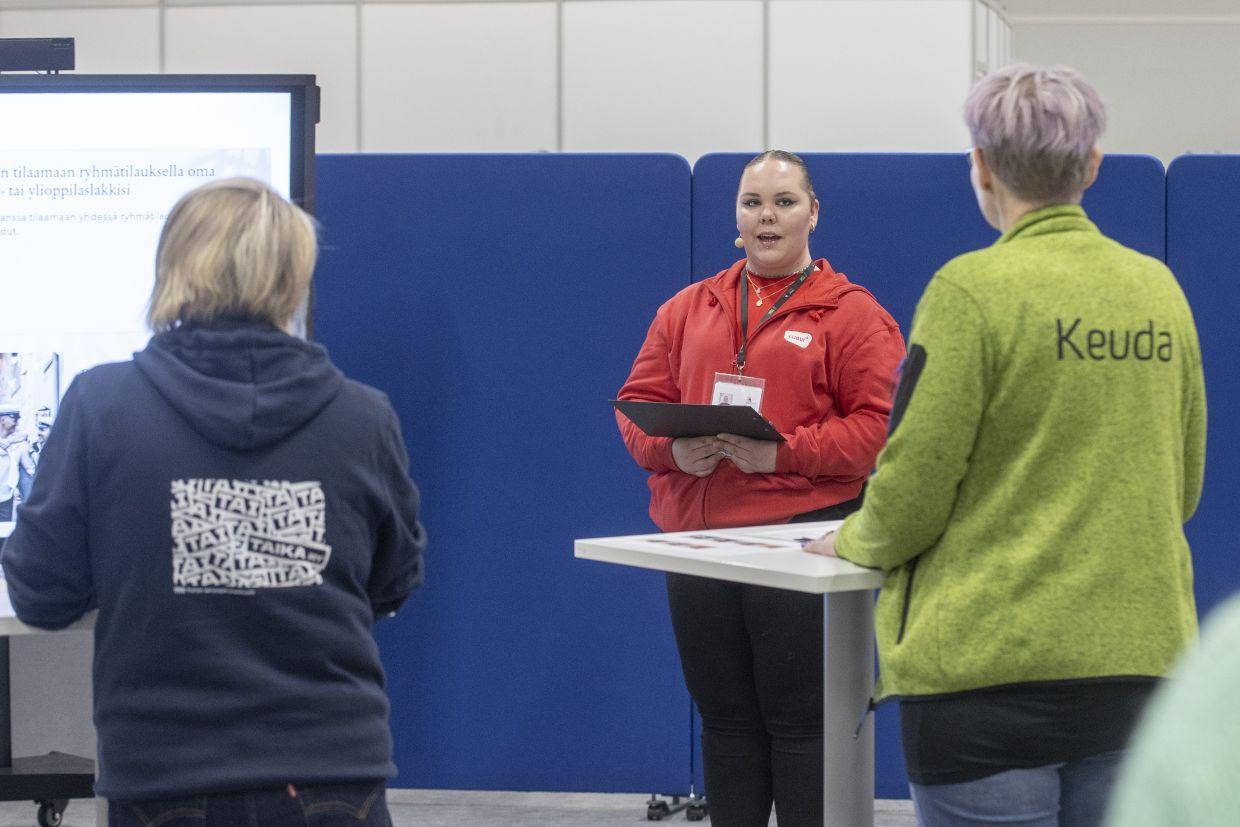 Person giving a presentation for two other people in competition setting.